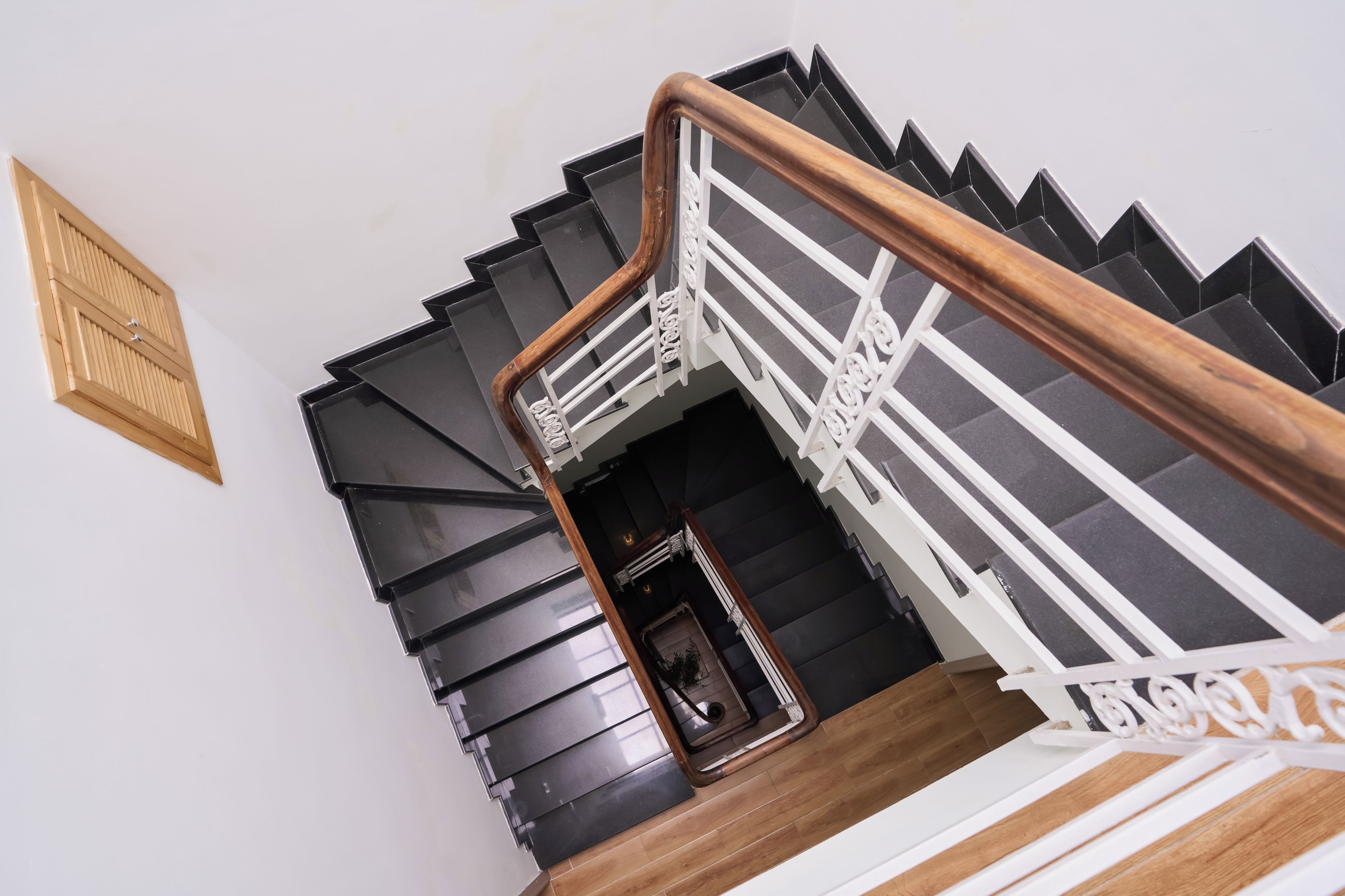 A spiral staircase with black steps and a wooden handrail.