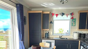 Una cocina moderna con armarios oscuros, una mesa de comedor con mantel a rayas y sillas de madera.