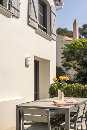 A patio table with chairs, a vase with flowers, and a magazine on the table.