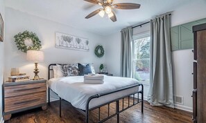 A bedroom with a bed, nightstand, lamp, and a ceiling fan. - The Dugout 3BR - Backyard & Game Room! (Woodstock)