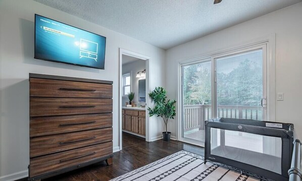 Een woonkamer met een televisie, een houten dressoir en uitzicht op het buitengebied.