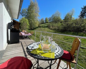 Una terrazza con tavolo apparecchiato per due, posti a sedere all'aperto e un barbecue.
