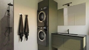 Ein kleiner Waschraum mit Waschmaschine, Wäscheständer und Dusche.