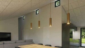 Eine moderne Küche mit Holztisch, grauem Sofa und Pendelleuchten.