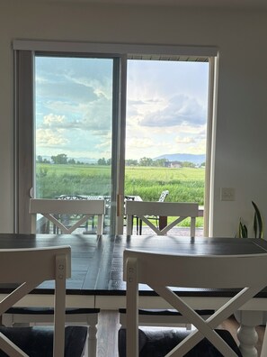 A room with a large sliding glass door leading to a patio with a table and chairs. - Bridger Mountain Vista-Private, Clean, Hot Tub, Stunning Rocky Mountain Views (Bozeman)