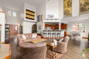 Ein geräumiges Wohnzimmer mit einer großen Couch, einem Holztisch und einer Küchenzeile mit Holzschränken und Barhocker.