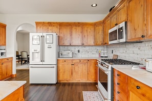 A kitchen with wooden cabinets, a white refrigerator, a microwave, a stove, and a toaster. - Bridger Mountain Vista-Private, Clean, Hot Tub, Stunning Rocky Mountain Views (Bozeman)