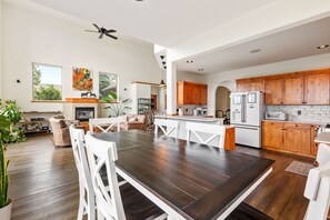 A spacious living area with a large wooden dining table, white chairs, and a kitchen with wooden cabinets and modern appliances. - Bridger Mountain Vista-Private, Clean, Hot Tub, Stunning Rocky Mountain Views (Bozeman)