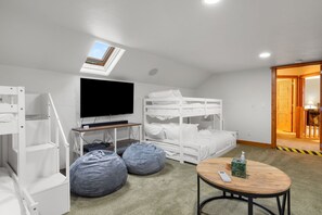 A room with bunk beds, a television, a desk, and bean bags.