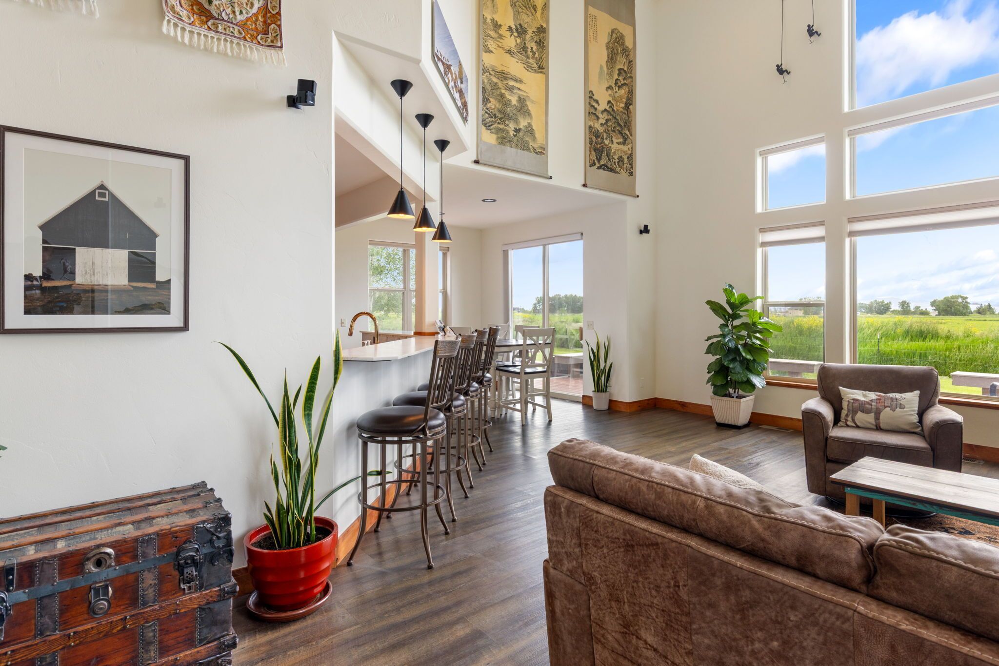 A spacious living area with a dining table, chairs, a sofa, and a view of the outdoors.
