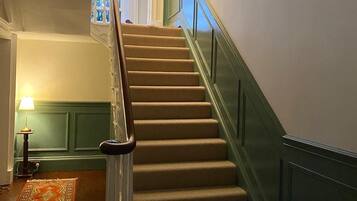 A staircase with a handrail, carpeted steps, and a green wall.