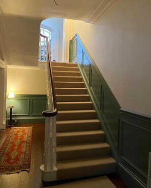 Eine Treppe mit Handlauf, Teppichstufen und einer grünen Wand.