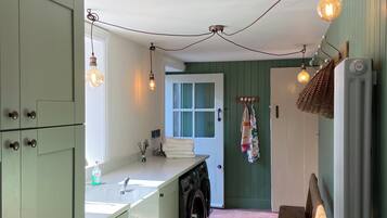 A kitchen with a washing machine, a bench, and hanging lights.