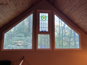 Ein Zimmer mit schrägem Dach und drei Fenstern mit Holzrahmen.
