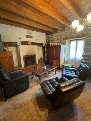 A cozy living room with a fireplace, leather sofas, a coffee table, and a stone wall. - Chez Patrick (Vitrac)