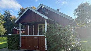 Ein eingeschossiges Haus mit Veranda, Schornstein und kleinem Garten.