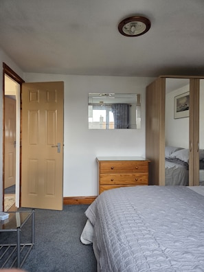 A bedroom with a bed, a wooden dresser, a mirror, a door, and a window. - The Loft Snug - Cosy Private Room, 20 Minute Train Access to Central London (London)