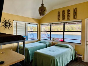 A room with bunk beds, a table, and large windows with a view of a dock and water. - The Famous FloatHouse • Stay ON Lake Travis • Unlike Anything Else (Leander)