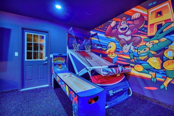 Una habitación con una máquina de baloncesto, una puerta con ventanal y un mural en la pared.