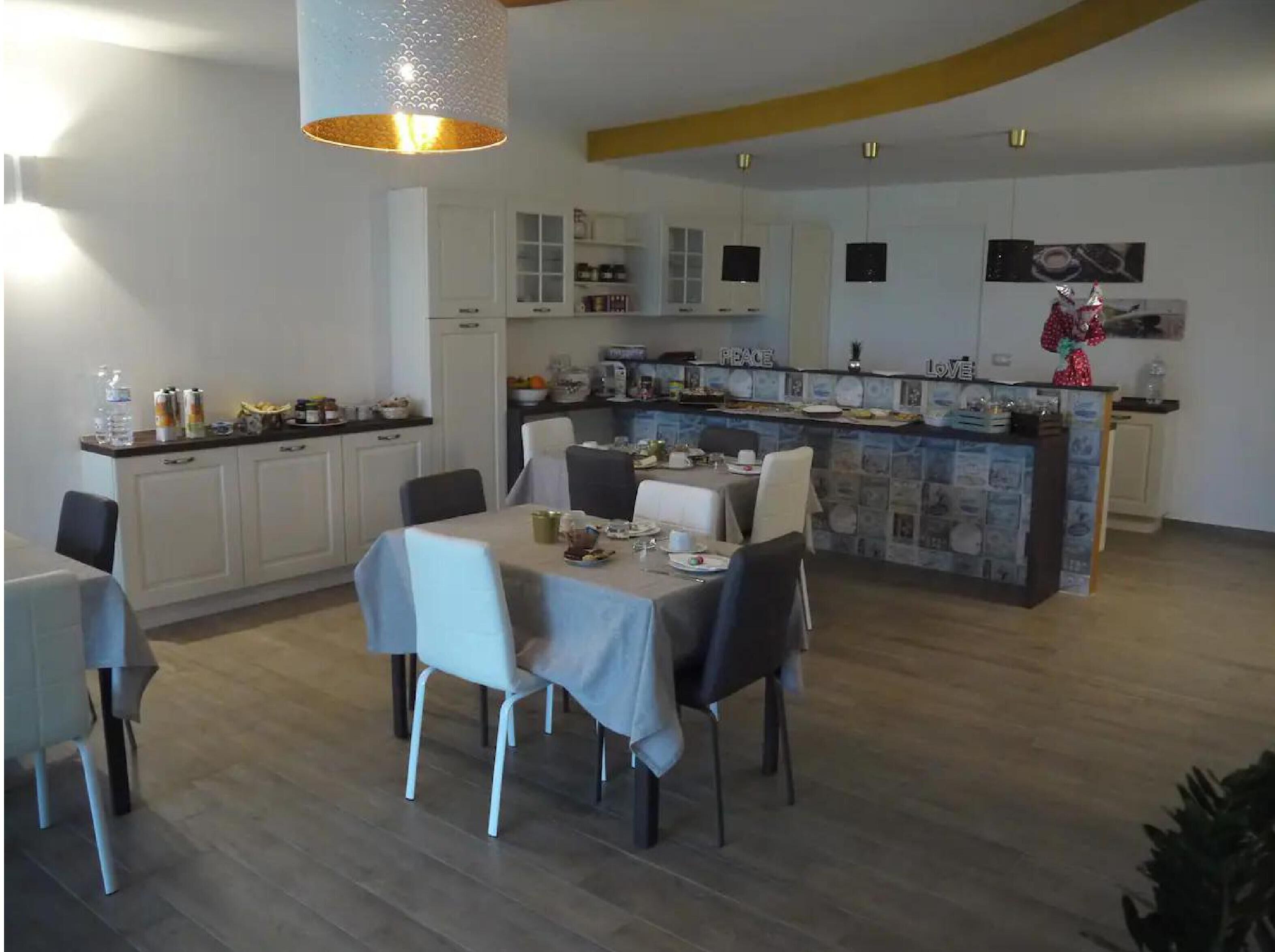 A modern kitchen with white cabinets, a dining area with a table set for four, and a bar area with a counter.