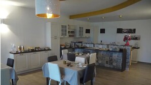 A modern kitchen with white cabinets, a dining area with a table set for four, and a bar area with a counter.