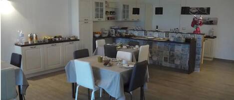 A modern kitchen with white cabinets, a dining area with a table set for four, and a bar area with a counter.