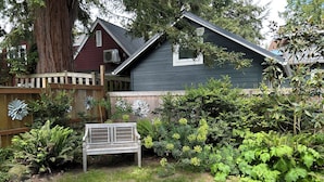 Un jardín con un banco, una valla de madera y una casa de techo oscuro.