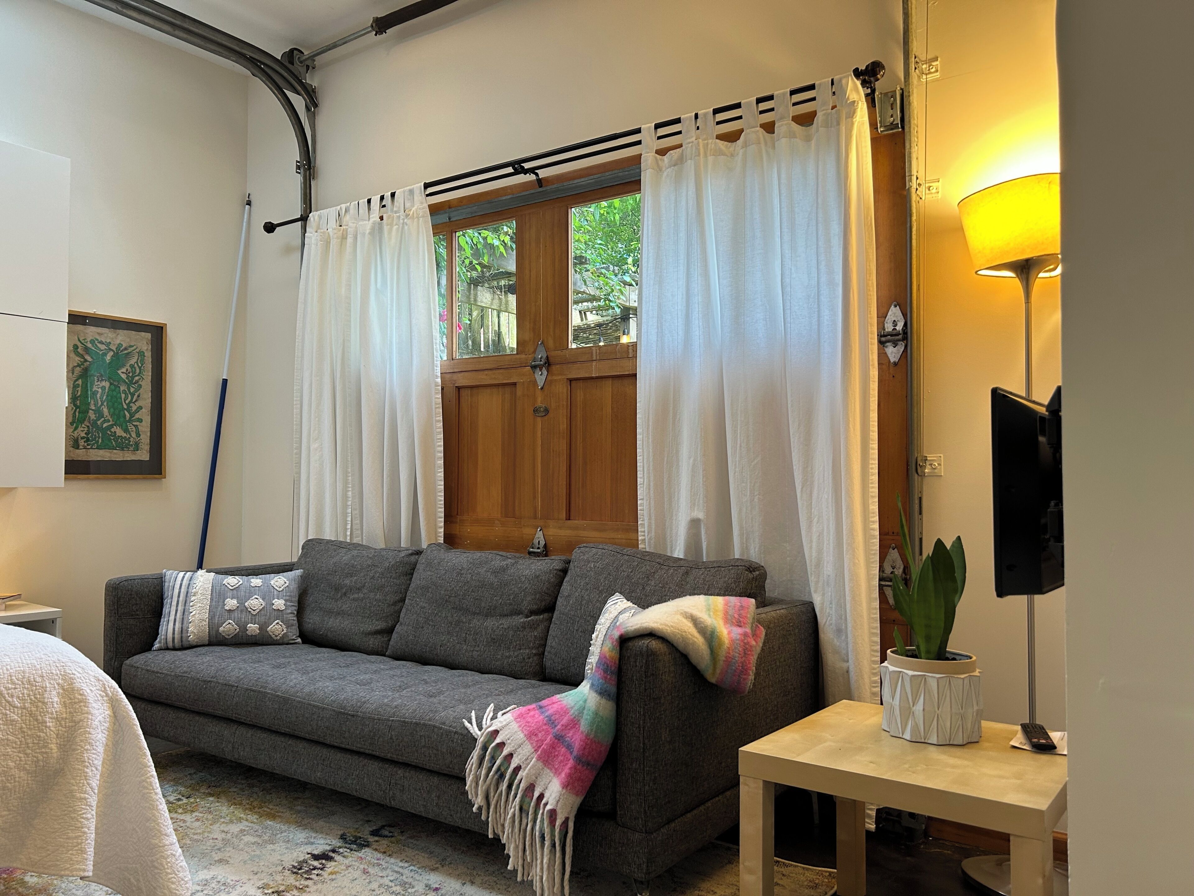 A cozy living room with a sofa, a small table, a lamp, and a potted plant.