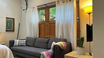 A cozy living room with a sofa, a small table, a lamp, and a potted plant.