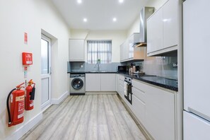 A modern kitchen with a washing machine, a microwave, and a stove. - Spacious 4-Bed Home in MCR Ideal for Groups (Manchester)