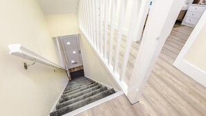 Un escalier avec une rampe, une porte et une balustrade blanche.