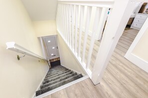 A staircase with a handrail, a door, and a white railing. - Spacious 4-Bed Home in MCR Ideal for Groups (Manchester)