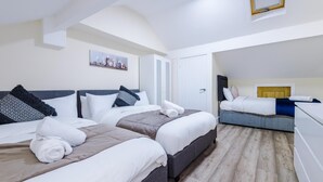 Une chambre d’hôtel avec deux lits, un petit bureau, une porte et un tableau au mur.