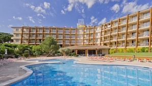 A hotel with a large swimming pool, multiple balconies, and a clear blue sky. - Apartment in Tossa de Mar Near Beach (Tossa de Mar)