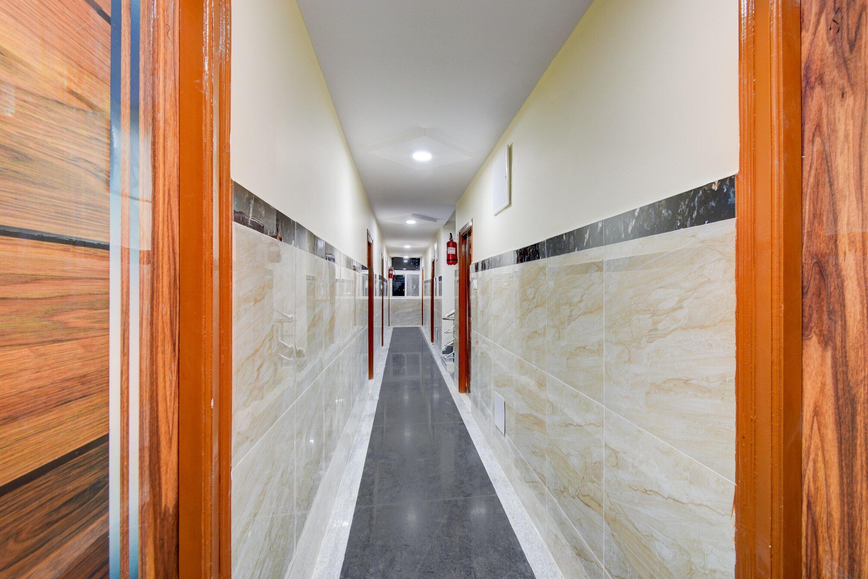 Un pasillo con paredes de mármol y suelo negro, que conduce a una puerta con un extintor.