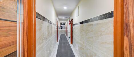 Un pasillo con paredes de mármol y suelo negro, que conduce a una puerta con un extintor.