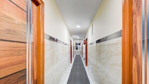 Un corridoio con pareti in marmo, porte in legno e pavimento piastrellato.
