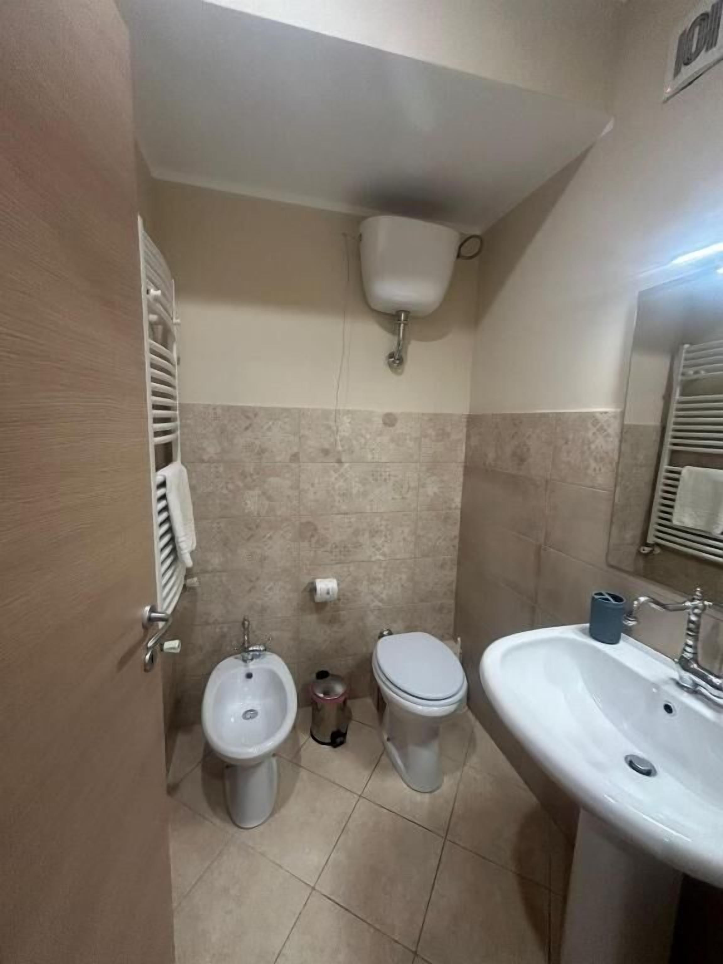 Une salle de bain équipée de toilettes, d’un bidet, d’un lavabo et d’un porte-serviettes.