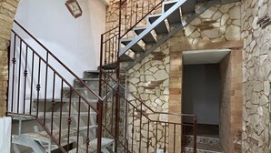 Una escalera con pared de piedra, barandales de metal y suelo estampado.