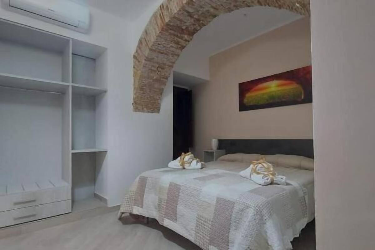A bedroom with a bed, a wardrobe, and a painting on the wall.