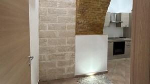 Un pasillo con suelo de baldosas, pared de ladrillo y puerta de madera.