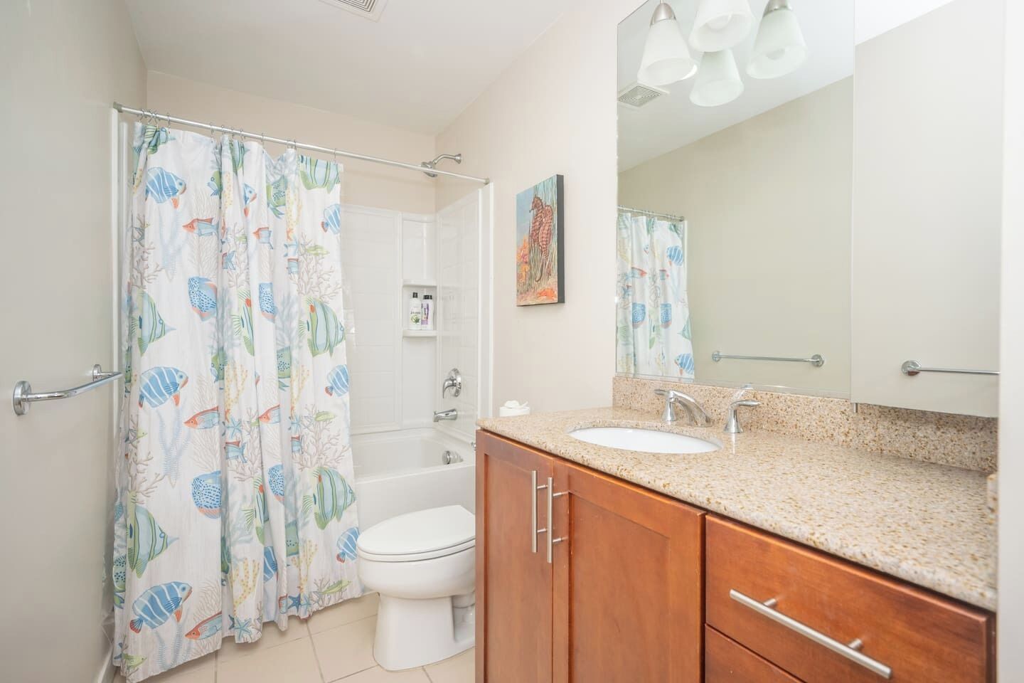 A bathroom with a shower curtain, toilet, sink, and wooden cabinets.