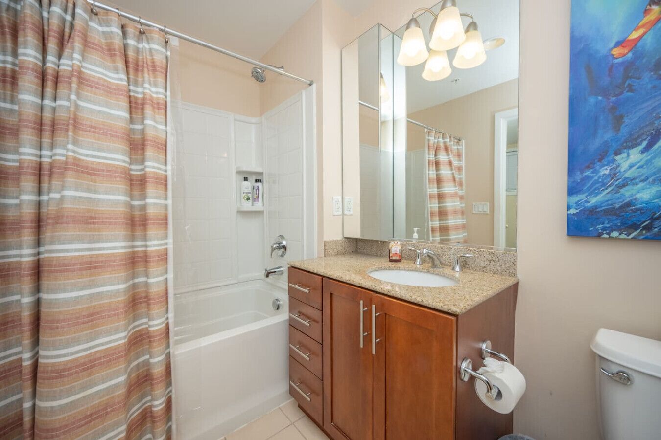 A bathroom with a shower, a sink, a mirror, and a toilet.
