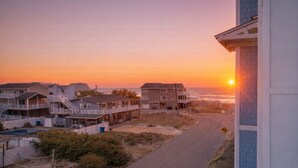 A coastal residential area with houses, a road, and a sunset.