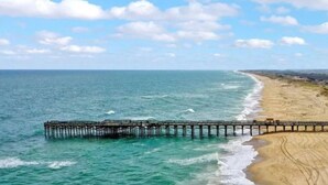 A beach with a wooden pier extending into the ocean.