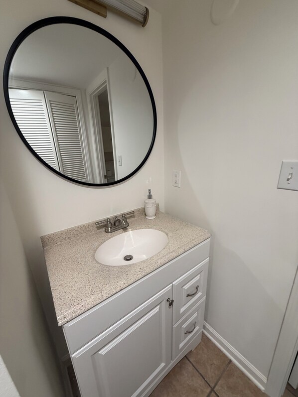 A bathroom with a white sink, a round mirror, and a cabinet with drawers. - Close to the Oxford Square! Quiet condo close to everything Oxford has to offer (Oxford)