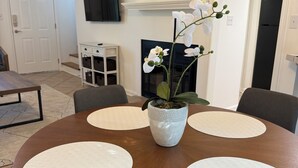Un tavolo da pranzo con quattro sedie, un'orchidea in vaso e un camino sullo sfondo.