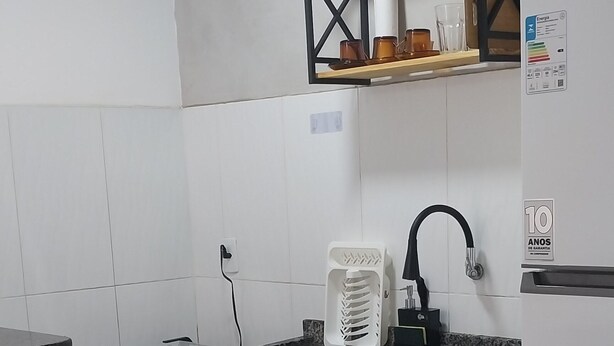 Une cuisine avec des armoires blanches, un four encastré, un plan de travail en granit, une machine à café et un réfrigérateur.