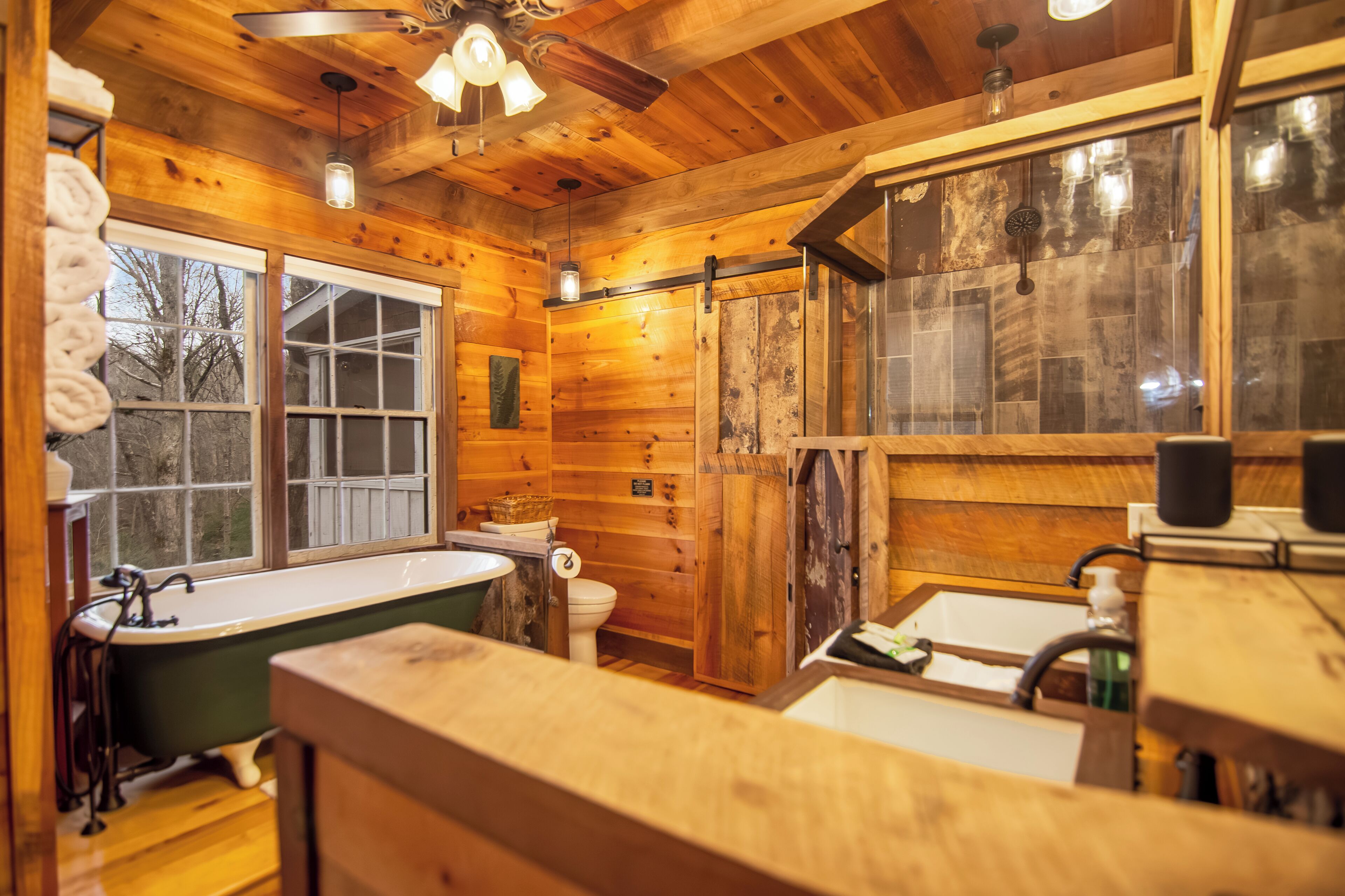 Een houten badkamer met een bad, toilet en wastafel.