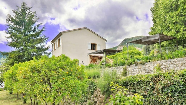 A building with a stone wall, a pergola, and a tree. - Apartment for 6 People (Le Bar-sur-Loup)